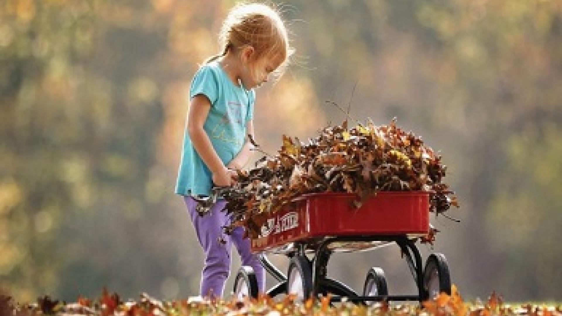 little girl pulling wagon with leaves