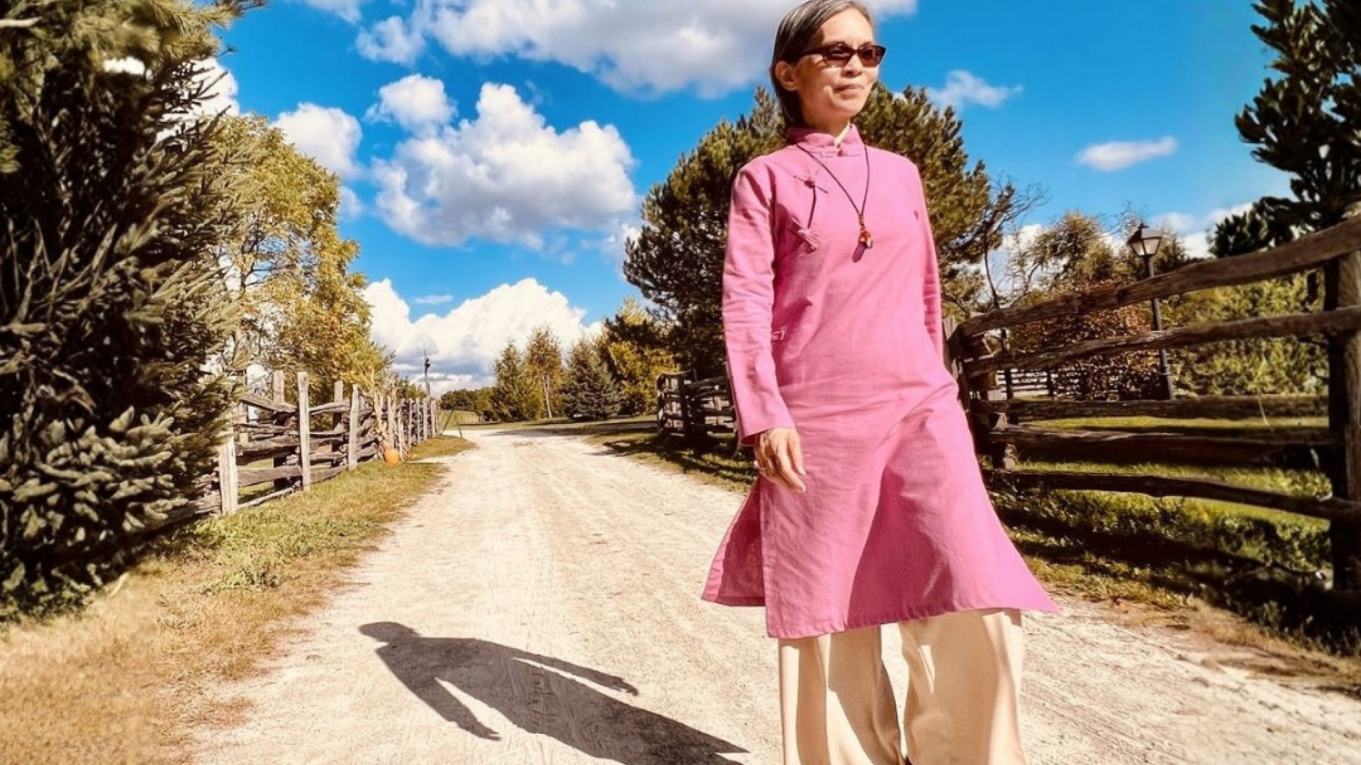 A woman walking down a dirt path with beige pants
