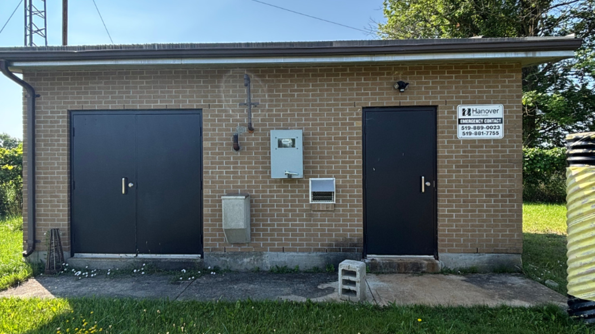 a brown flat roofed building with dark brown doors and a Town of Hanover logo, it is one of the Town of Hanover buildings that house the wells