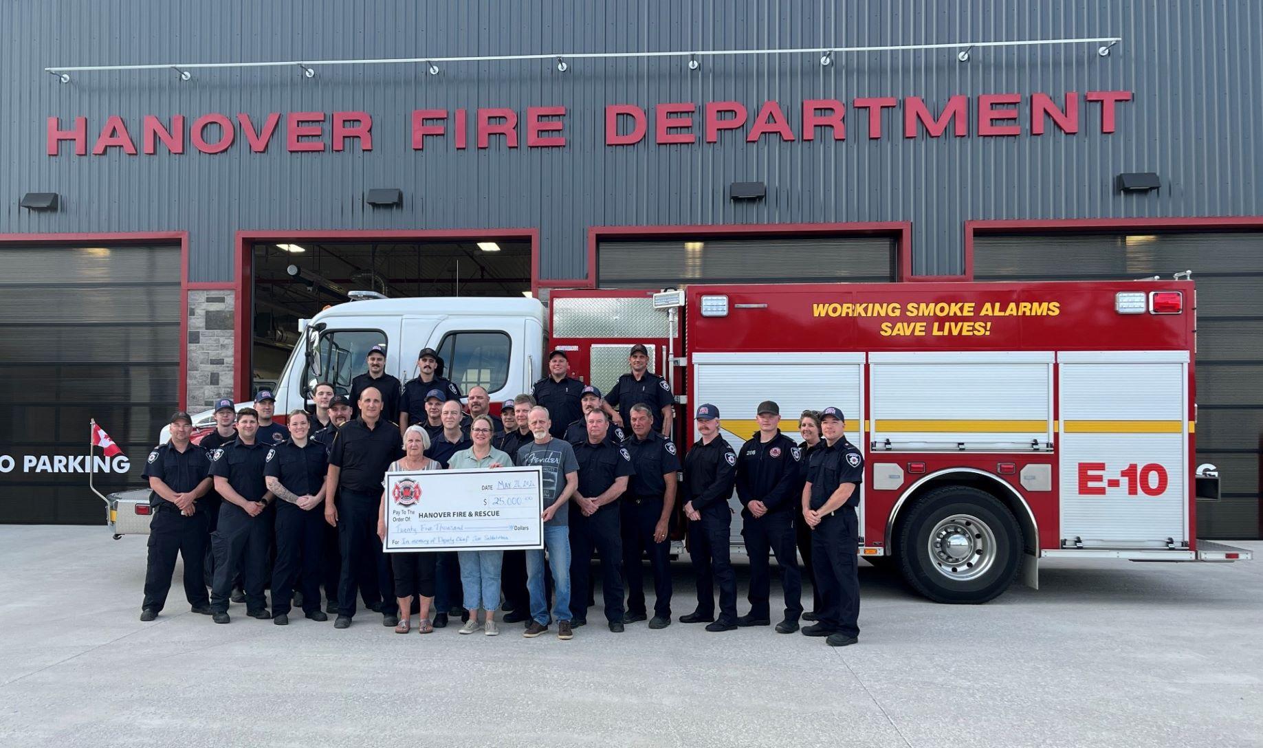Hanover Fire Department members in front of truck with family for cheque presentation